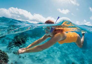 Woman snorkeling in clear turquoise lagoon waters in the Cook Islands during South Pacific cruise