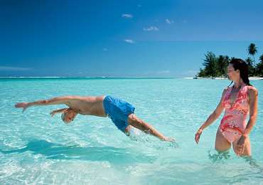 Couple swimming in crystal-clear turquoise lagoon in the Cook Islands during South Pacific cruise