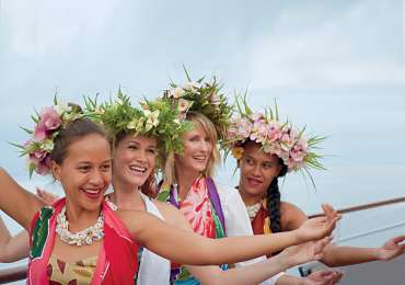 Polynesian dancers welcoming Windstar Cruises guests in Tahiti with traditional flower crowns and island attire