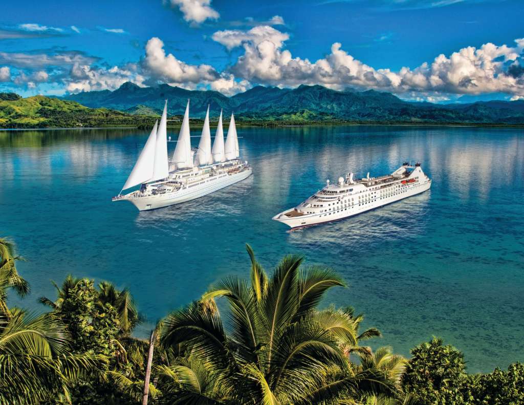 Windstar Cruises small luxury ships sailing in Bora Bora lagoon, French Polynesia with turquoise waters and tropical mountains
