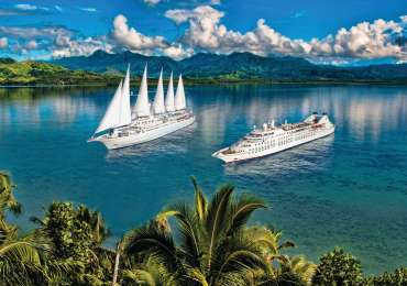 Windstar Cruises small luxury ships sailing in Bora Bora lagoon, French Polynesia with turquoise waters and tropical mountains