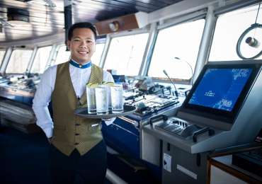 Windstar Cruises crew member serving welcome drinks aboard luxury small ship yacht in French Polynesia